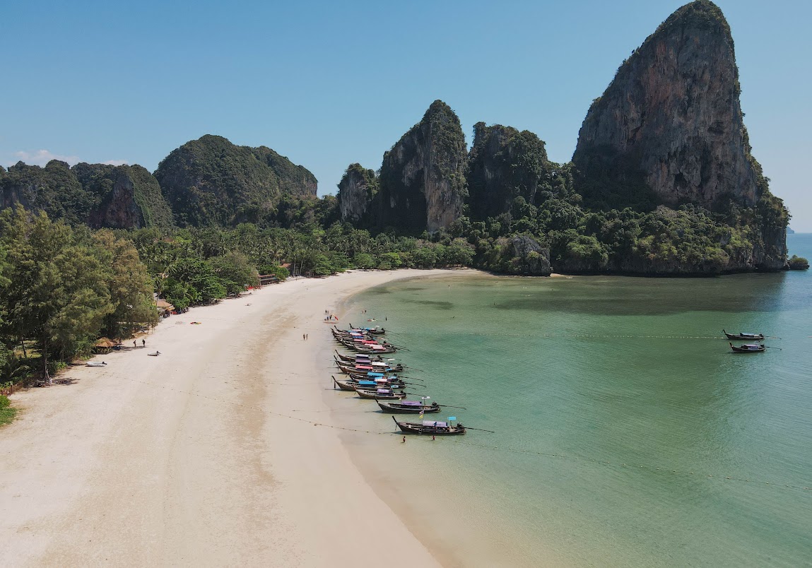 Longtail boats anchored at Railay Beach surrounded by limestone cliffs in Krabi